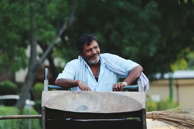 Man looking away while holding garbage can