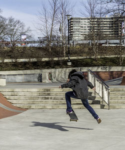 Rear view of man skateboarding in park