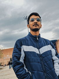 Portrait of young man standing against sky