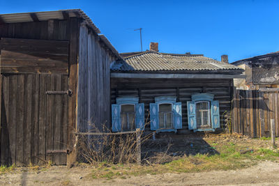 Old abandoned house on field against clear blue sky