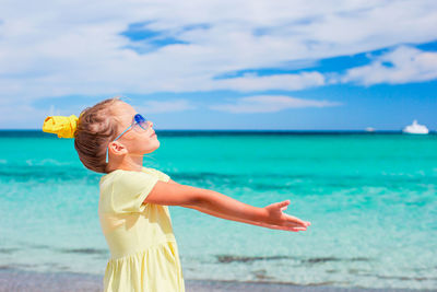 Rear view of woman standing at beach against sky