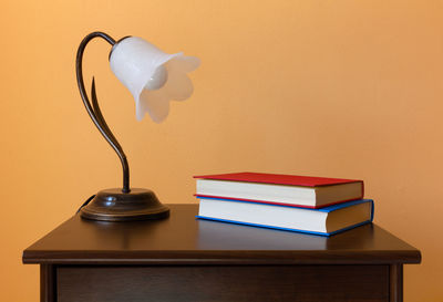 Close-up of electric lamp on table against wall