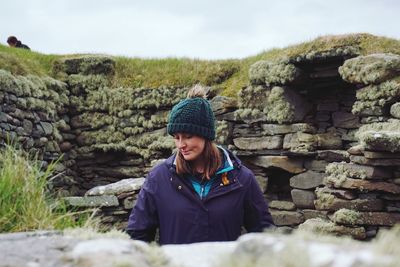 Young woman wearing warm clothing while looking down at remote location