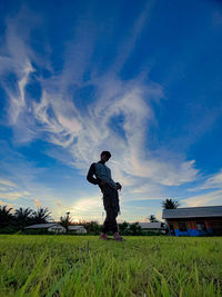 Man standing on field against sky during sunset