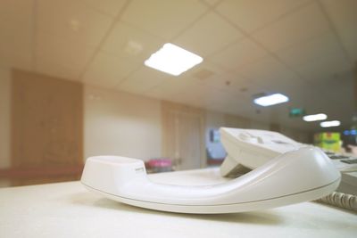 Close-up of electric lamp on table against wall