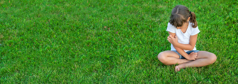 Side view of girl playing with ball on grassy field