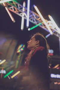 Mid adult woman looking up against illuminated stage