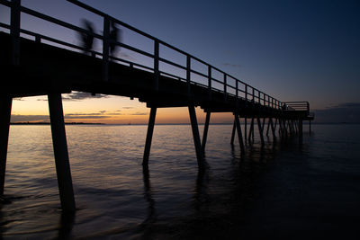 Silhouette pier over sea against sky during sunset