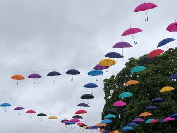 Low angle view of multi colored umbrellas hanging against sky