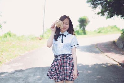 Young woman standing on road against sky