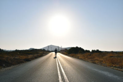 Man on road against clear sky on sunny day