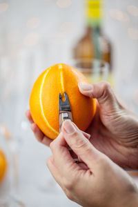 Cropped image of hands peeling orange fruit