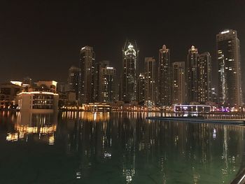 Illuminated modern buildings in city against sky at night