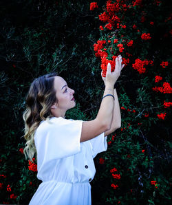 Beautiful woman standing by red flowering plants