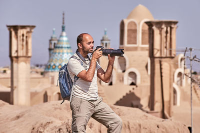 Young man holding umbrella against building