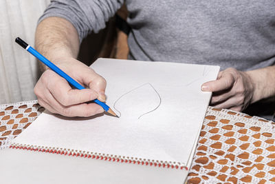 Midsection of man holding paper with text on table