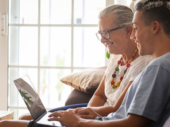 Side view of grandmother and grandson using laptop at home