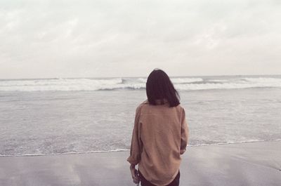 Rear view of woman looking at sea against sky
