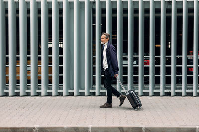 Side view of man with luggage walking on footpath