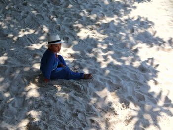 High angle view of boy sitting on sand at beach
