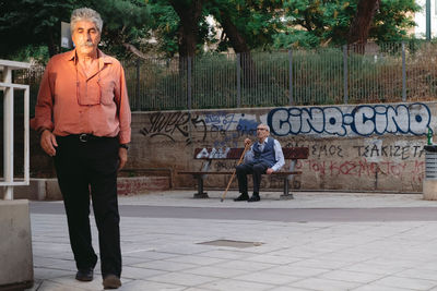Full length portrait of man standing on footpath