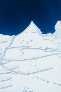 Snow covered landscape against blue sky