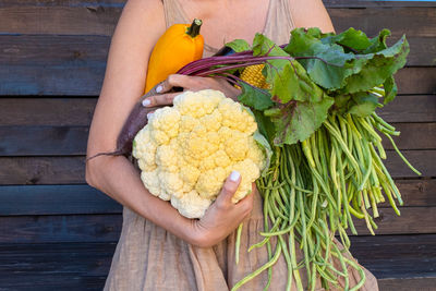 Eco-friendly concept with organic farm vegetables in the hands of a girl in a linen dress