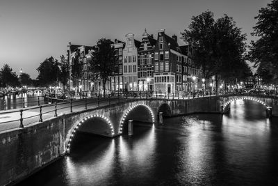 Illuminated bridge over river at night