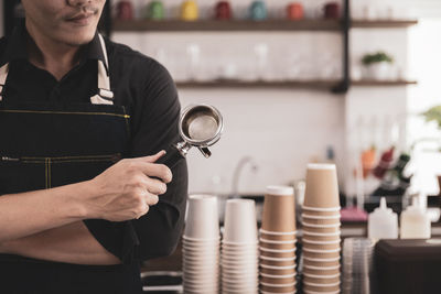 Midsection of man holding tea strainer while working in kitchen