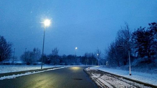 Road passing through illuminated lights at night