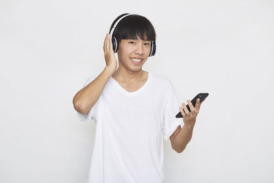 Young man using smart phone against white background