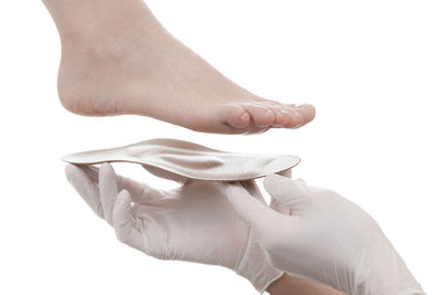 Cropped hand of doctor holding insoles by patient feet