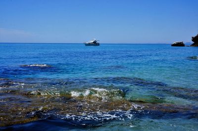 Boat sailing in sea against clear sky