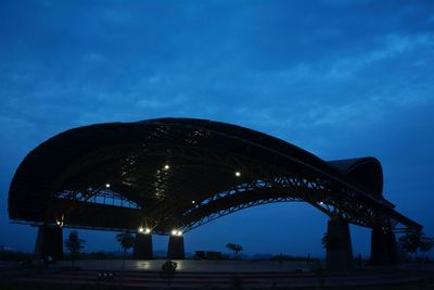 Illuminated bridge against blue sky at night