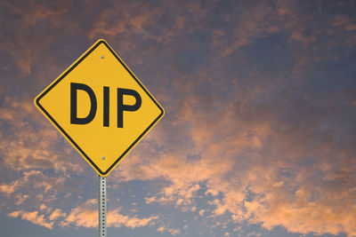 Low angle view of road sign against sky during sunset