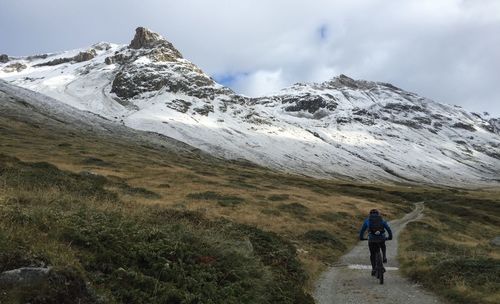 Rear view of man cycling on mountain road