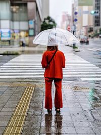 Rear view of man standing on wet street during monsoon