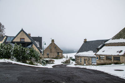 Houses by road in city against clear sky