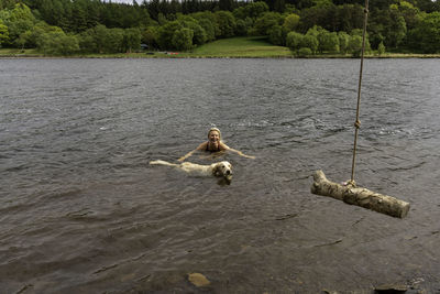 High angle view of woman swimming with dog in lake