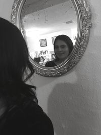 Rear view of woman standing in mirror