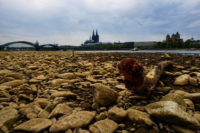 View of pebbles on rock by river against sky