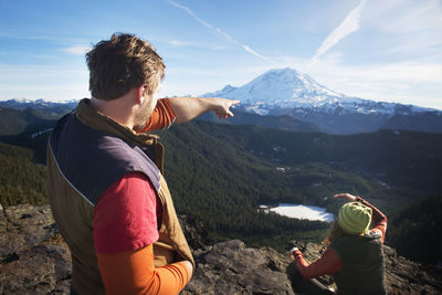 Side view of woman sitting on mountain against sky