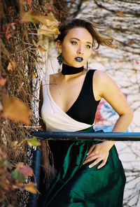 Portrait of young woman standing against tree