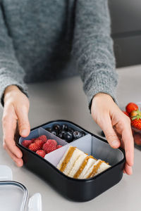 Mother prepares a lunch box with snacks lunch for her school child in the kitchen.