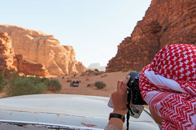 Rear view of man photographing at desert