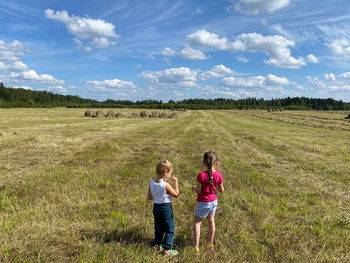 Rear view of women on field against sky