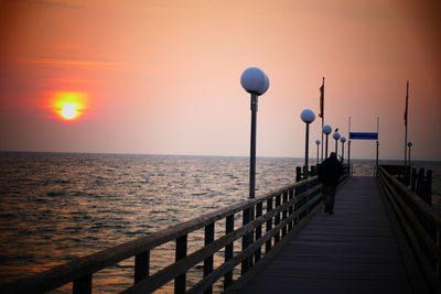 Pier over sea against sky during sunset