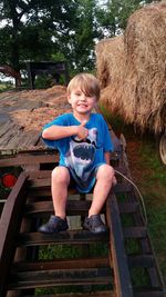 Portrait of smiling boy sitting on steps against trees