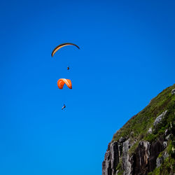 Low angle view of paragliding against blue sky