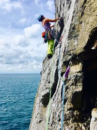 Woman climbing rock by sea